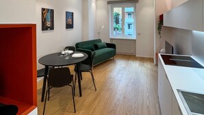 A modern apartment with a dining area, a green sofa, and a kitchen. - 4bnb - Charming Giuliana Apartment (Rome)