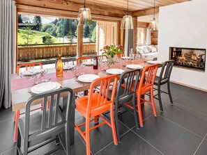 Enjoy meals in this dining area with a long table, comfortable chairs, and a beautiful view of the surrounding landscape.
