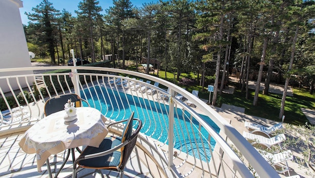 A pool area with a curved white railing, lounge chairs, and a table with a floral tablecloth. - Apartman Villa Ljiljana 5 (Jadranovo)