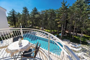 A pool area with a curved white railing, lounge chairs, and a table with a floral tablecloth. - Apartman Villa Ljiljana 5 (Jadranovo)