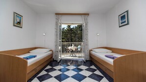 A room with two wooden beds, a checkered floor, and a balcony with a table and chairs. - Apartman Villa Ljiljana 5 (Jadranovo)