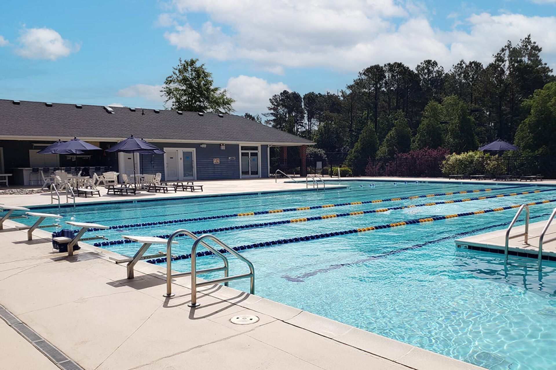 A swimming pool with multiple lanes, lounge chairs, and umbrellas.