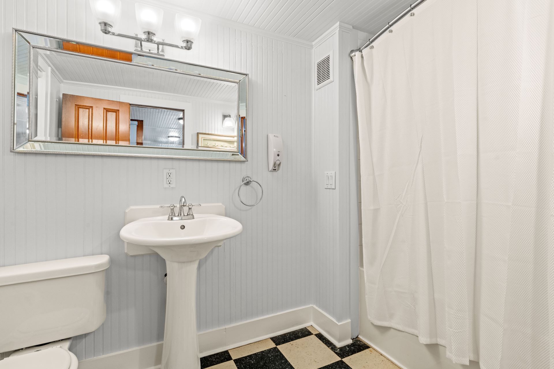 A bathroom with a white sink, a toilet, a mirror, and a shower curtain.