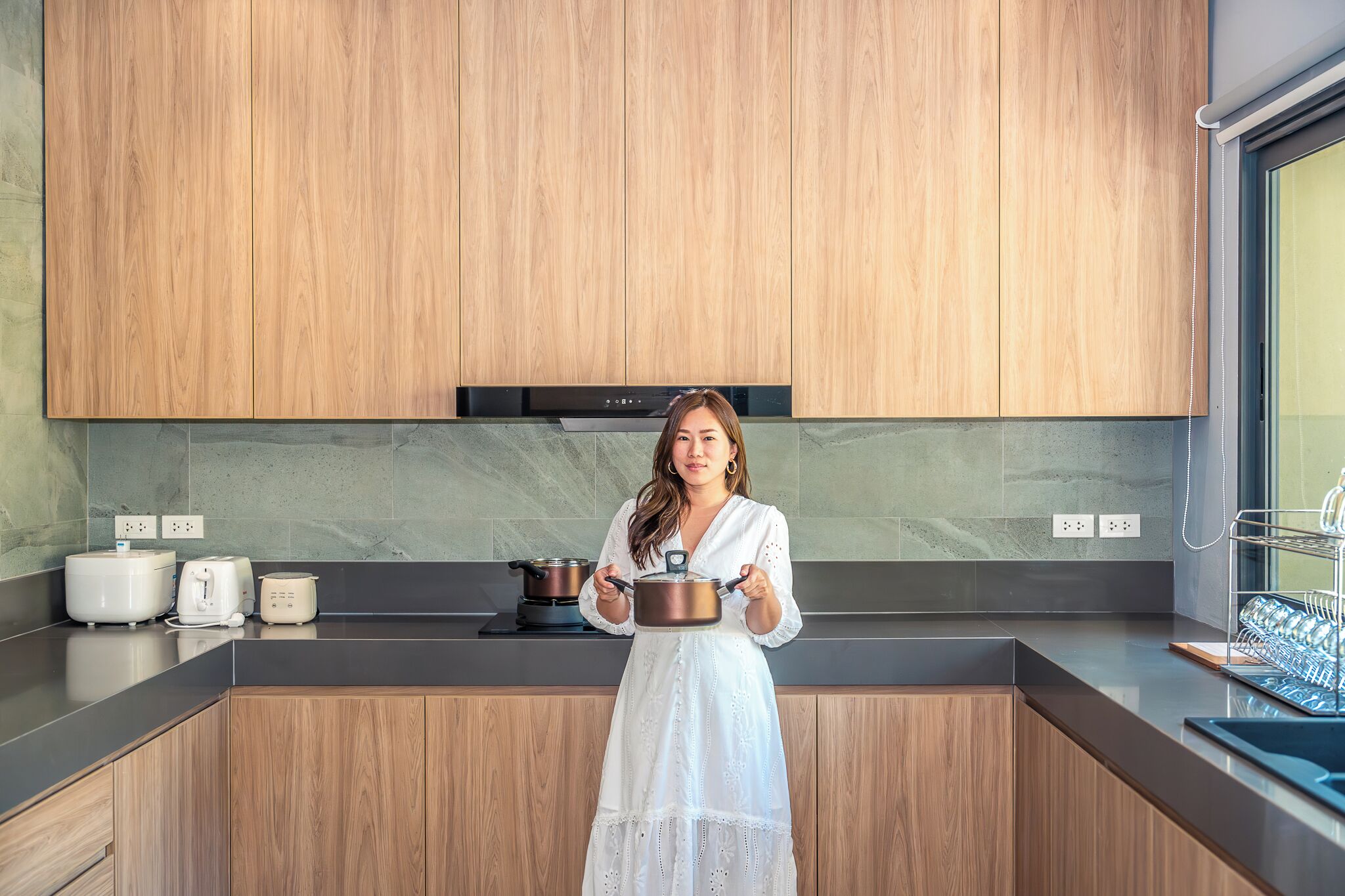 A modern kitchen with wooden cabinets, a marble backsplash, and a stainless steel range hood.