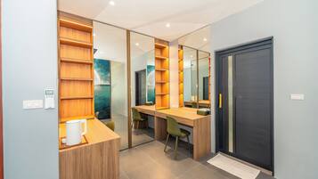 Un espacio de oficina moderno con un escritorio de madera, sillas verdes, una estantería y una puerta oscura.