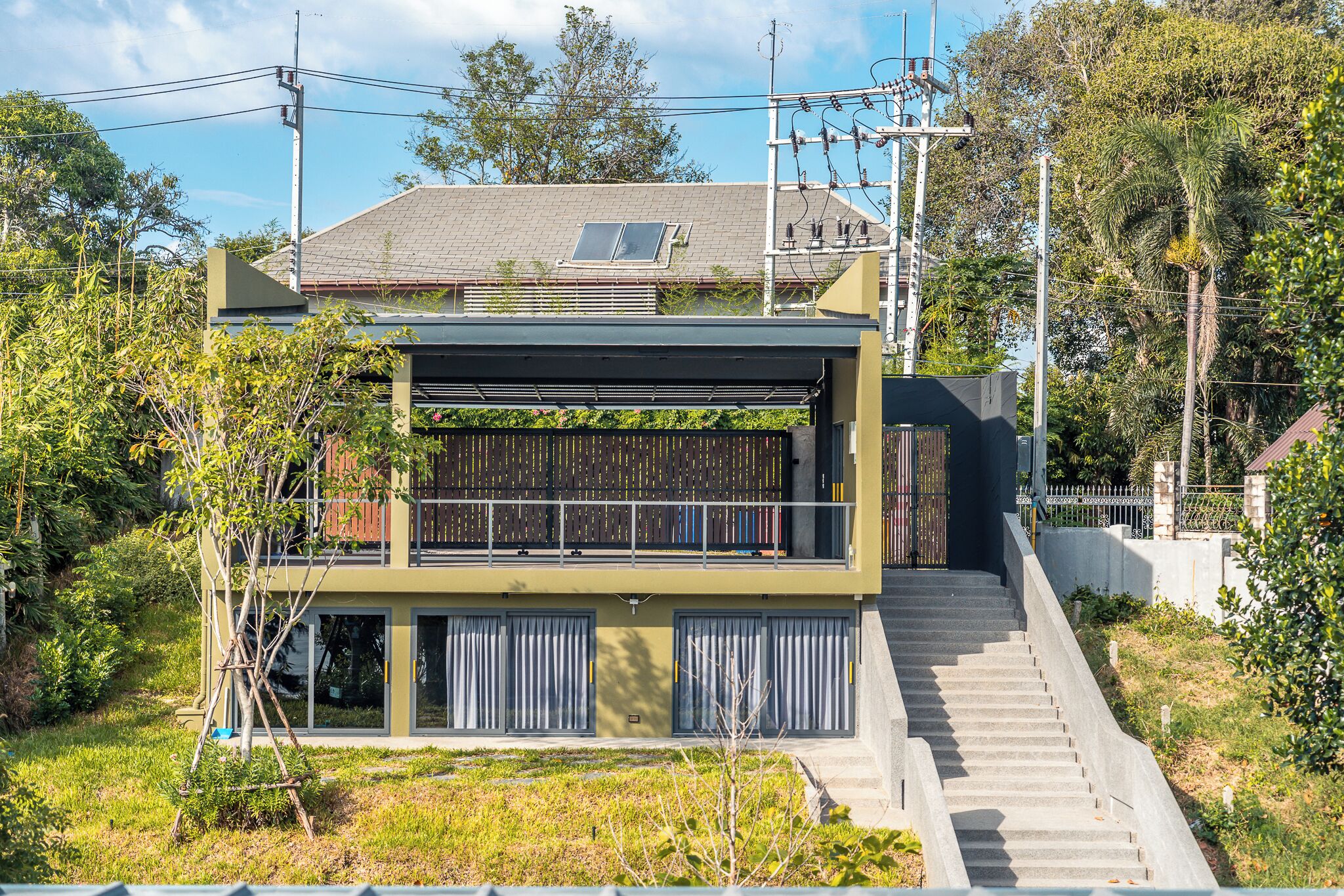 A modern two-story building with a flat roof, large windows, and a covered outdoor area.