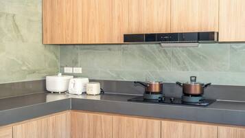 A modern kitchen with wooden cabinets, a black range hood, a gas stove, a kettle, and a toaster.