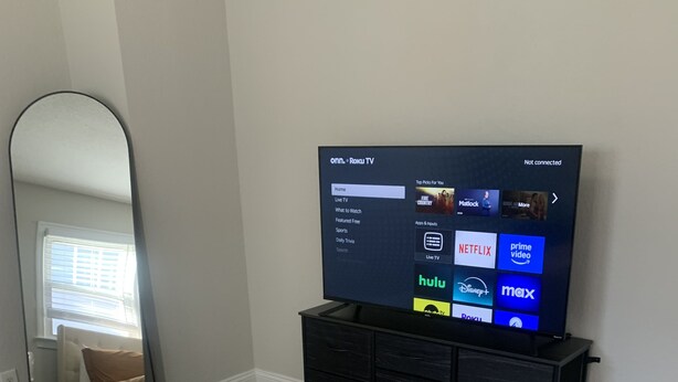 A bedroom with a bed, a dresser, and a television displaying a streaming service interface. - Welcome to our Place (Charlotte)
