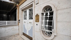 A building with a number 12 sign, a large arched window with a metal grille, and a door with decorative glass panels. - Boutique Suite Valadier (Rome)