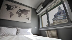 A bedroom with a bed, a world map on the wall, and a window with a view of a building. - Boutique Suite Valadier (Rome)