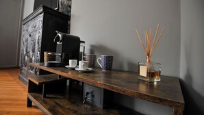 A wooden coffee table with a coffee maker, two patterned cups, and a reed diffuser. - Boutique Suite Valadier (Rome)