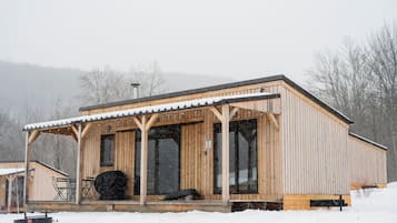 A wooden cabin with a covered porch, large windows, and a snow-covered roof.