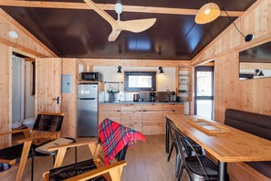 A compact kitchen with wooden walls, a central island, and a ceiling fan. - Huttopia Berkshires  (Williamstown)