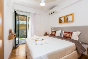 A hotel room with a bed, a nightstand, a wall-mounted air conditioner, and a sliding glass door leading to an outdoor area.
