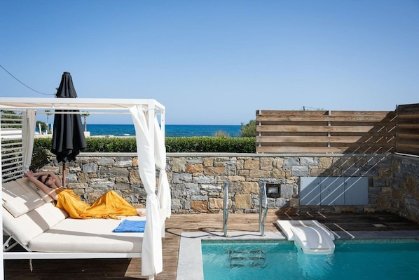 A poolside area with a white lounge chair, a yellow towel, and a wooden deck.
