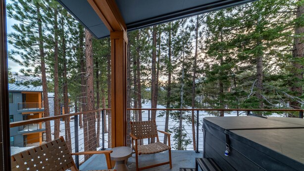 Ein Balkon mit Holzstuhl, rundem Tisch und Whirlpool.
