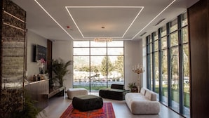 Una sala de estar moderna con ventanas amplias, una araña y una variedad de opciones de asientos.
