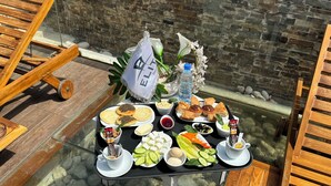 A table set with various food items and a water bottle, placed outdoors with a stone wall in the background. - Elite Hotel By Beverly (Beirut)