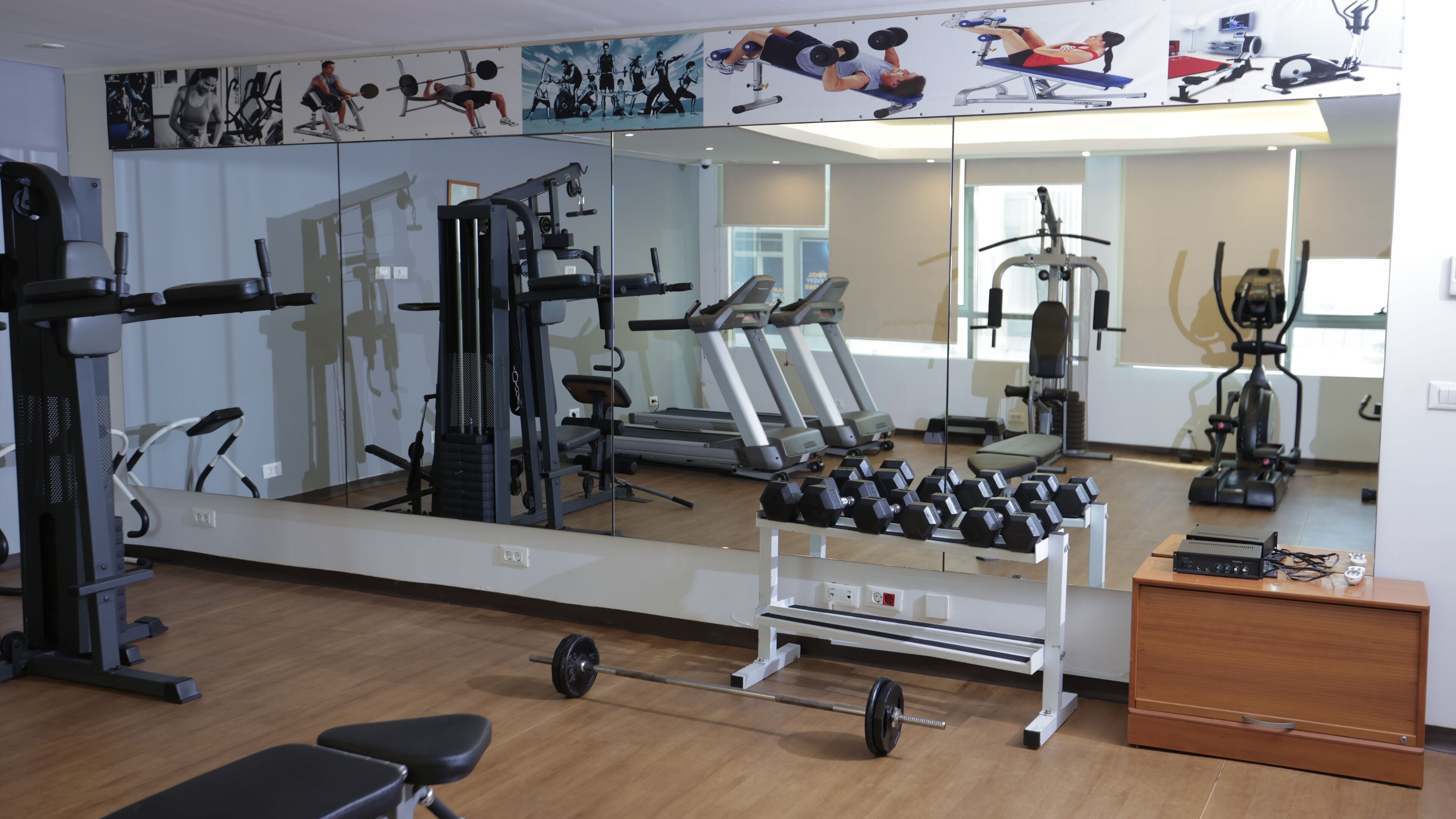 Uma academia com equipamentos de exercício, espelhos e piso de madeira.