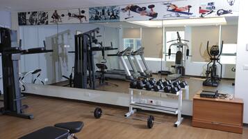 Uma academia com equipamentos de exercício, espelhos e piso de madeira.