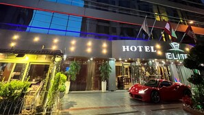 A modern hotel with a glass facade, a red sports car parked in front, and a sign reading "HOTEL ELITE". - Elite Hotel By Beverly (Beirut)