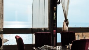 A dining table set for two with a view of the sea through a window. - Elite Hotel By Beverly (Beirut)