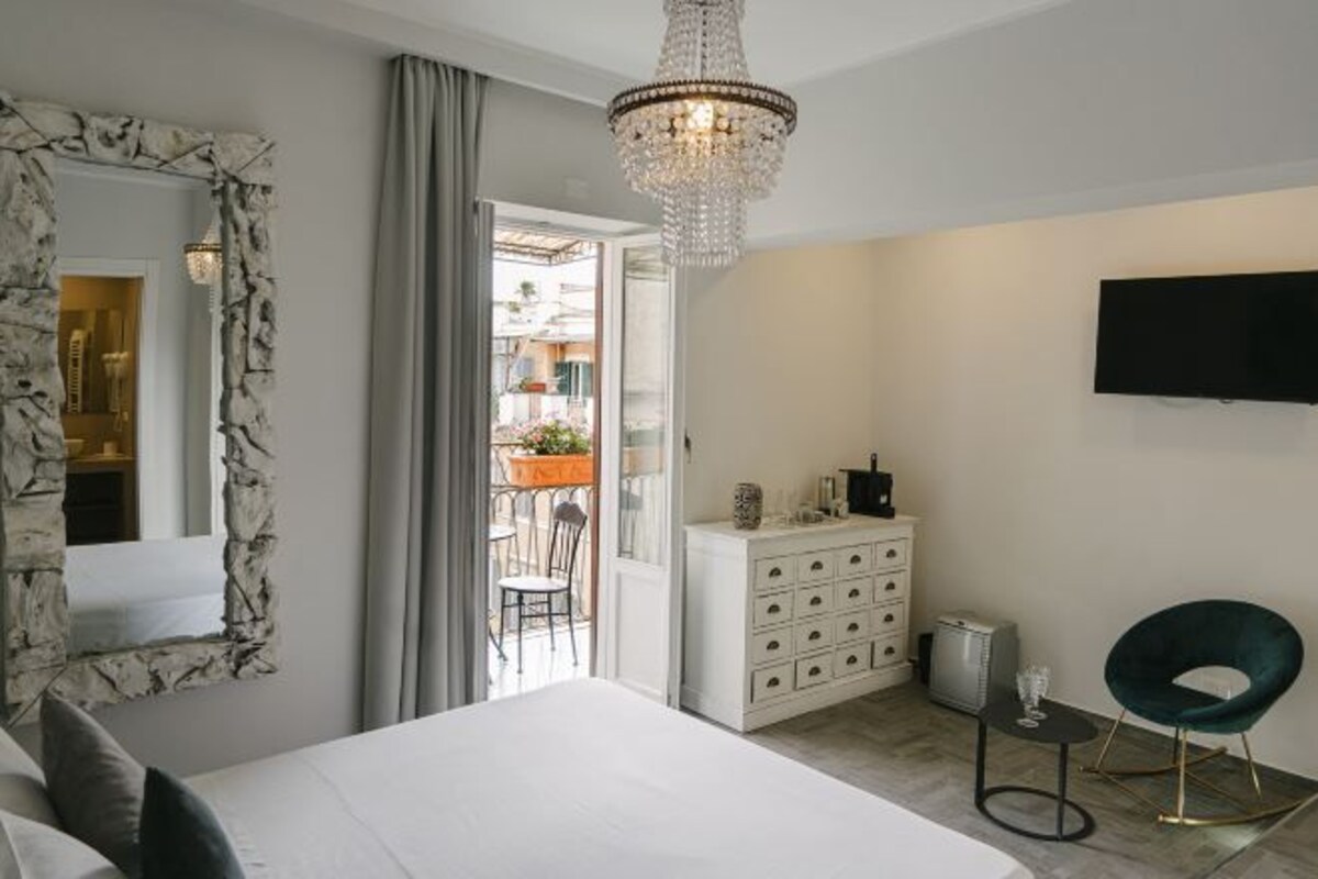 A bedroom with a large bed, a dresser, a television, and a chair.