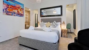 Une chambre d’hôtel moderne avec un grand lit, un lustre, un miroir et un tableau au mur.