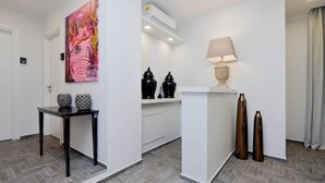Un hall d’hôtel moderne avec un sol en parquet à chevrons, une table noire agrémentée de vases décoratifs, un grand tableau abstrait et une lampe posée sur un piédestal.
