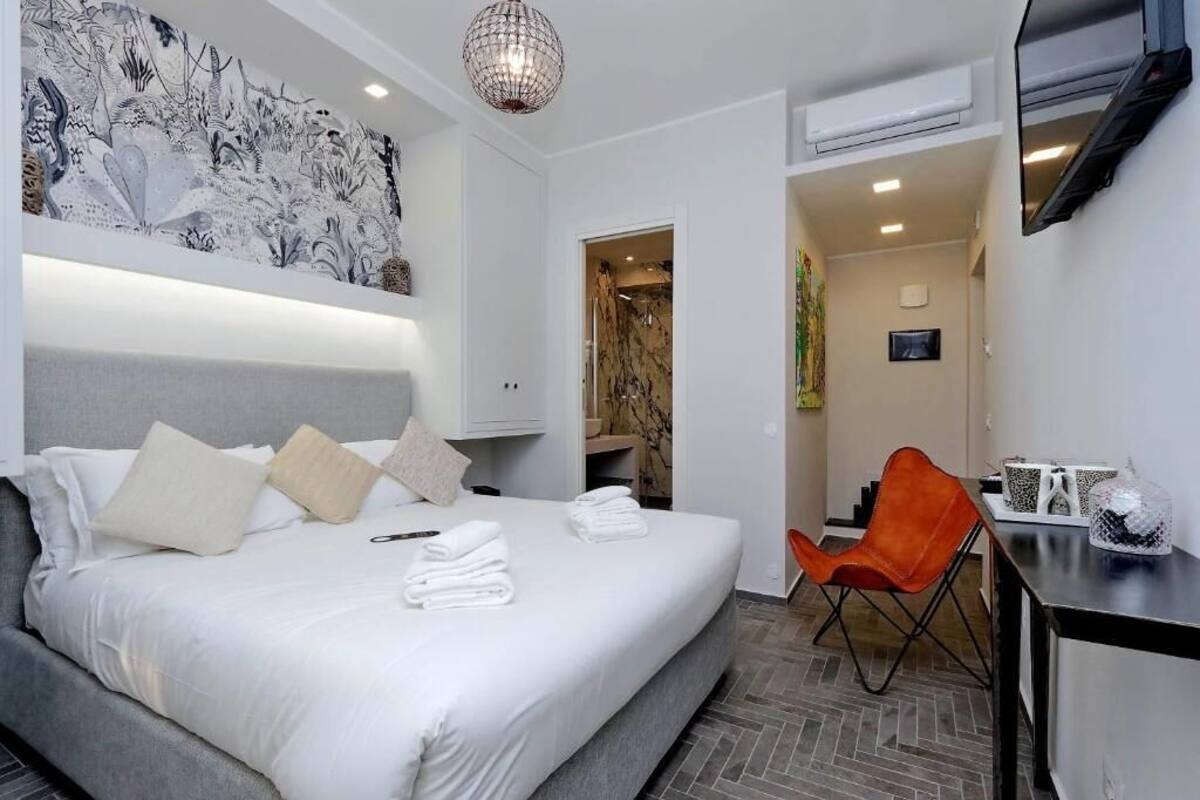 A modern hotel room with a large bed, a desk, and a chair.
