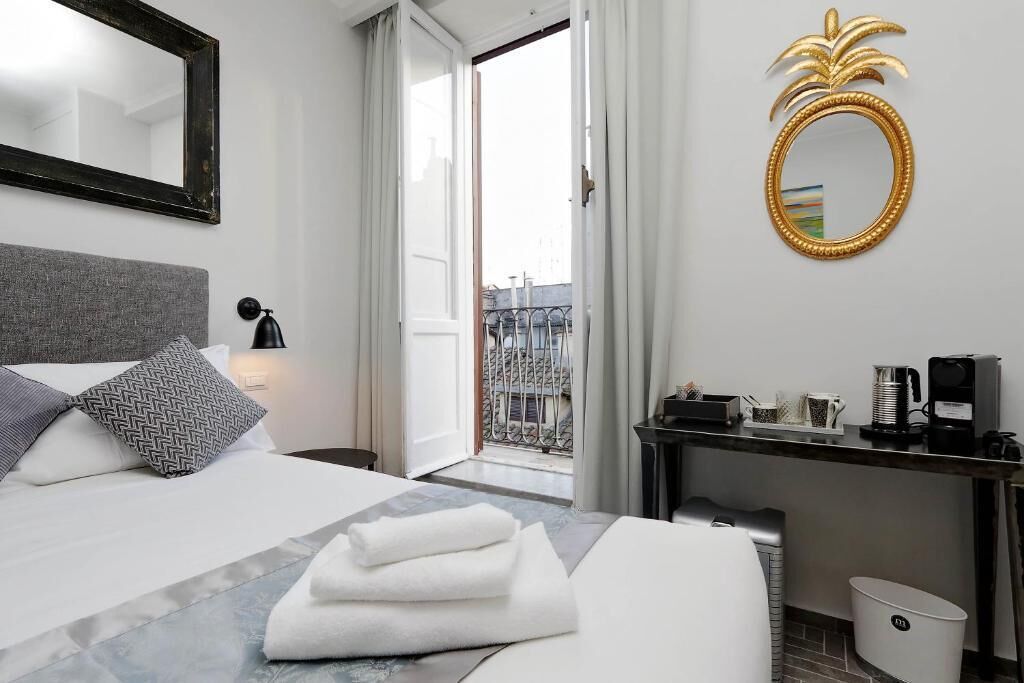 A hotel room with a bed, a desk, a coffee machine, and a view of the city.