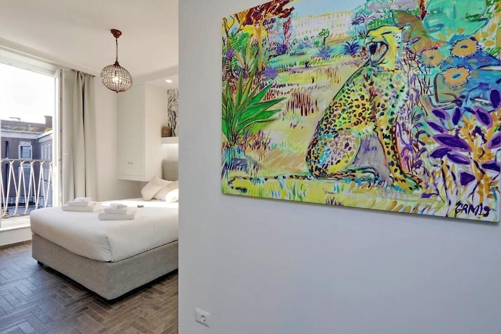 A modern bedroom with a large bed, a hanging light fixture, and a colorful painting on the wall.