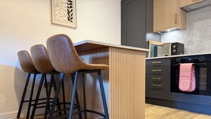 Uma cozinha com ilha de madeira, banquetas pretas, micro-ondas e forno preto.