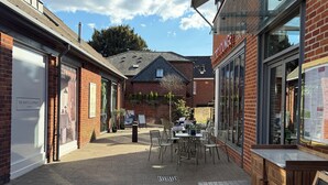 Um pátio com área de estar ao ar livre, um café e uma loja chamada "The White Company".
