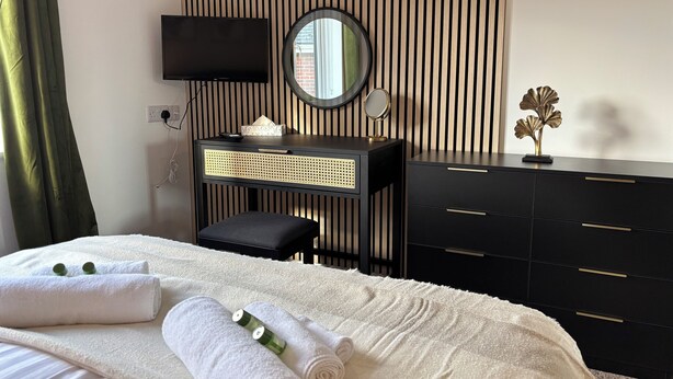 Quarto de hotel com cama, toucador com espelho, televisão de ecrã plano e cómoda.