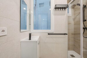 A modern bathroom with a shower, a sink, and a window. - La Latina Jewel Seasonal Rental (Madrid)