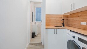 Una cocina compacta con cubierta de madera, un lavamanos y una lavadora.