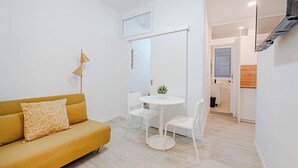 Una sala de estar moderna con un sofá, una mesita redonda y una silla blanca.