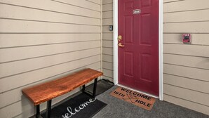 A red door with a fire alarm and a welcome mat. - 19th Hole 3 Bedroom Condo on the 9th Green (Maggie Valley)