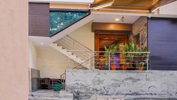 A modern staircase with marble steps and metal railings, leading to a landing area with potted plants and a view of the building's exterior. - RG Suites HSR (Bengaluru)