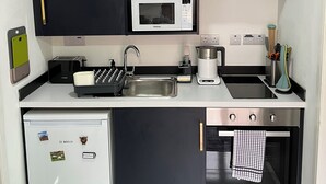 Kompakti keittiö, jossa on mikroaaltouuni, leivänpaahdin, pesuallas ja pieni jääkaappi.