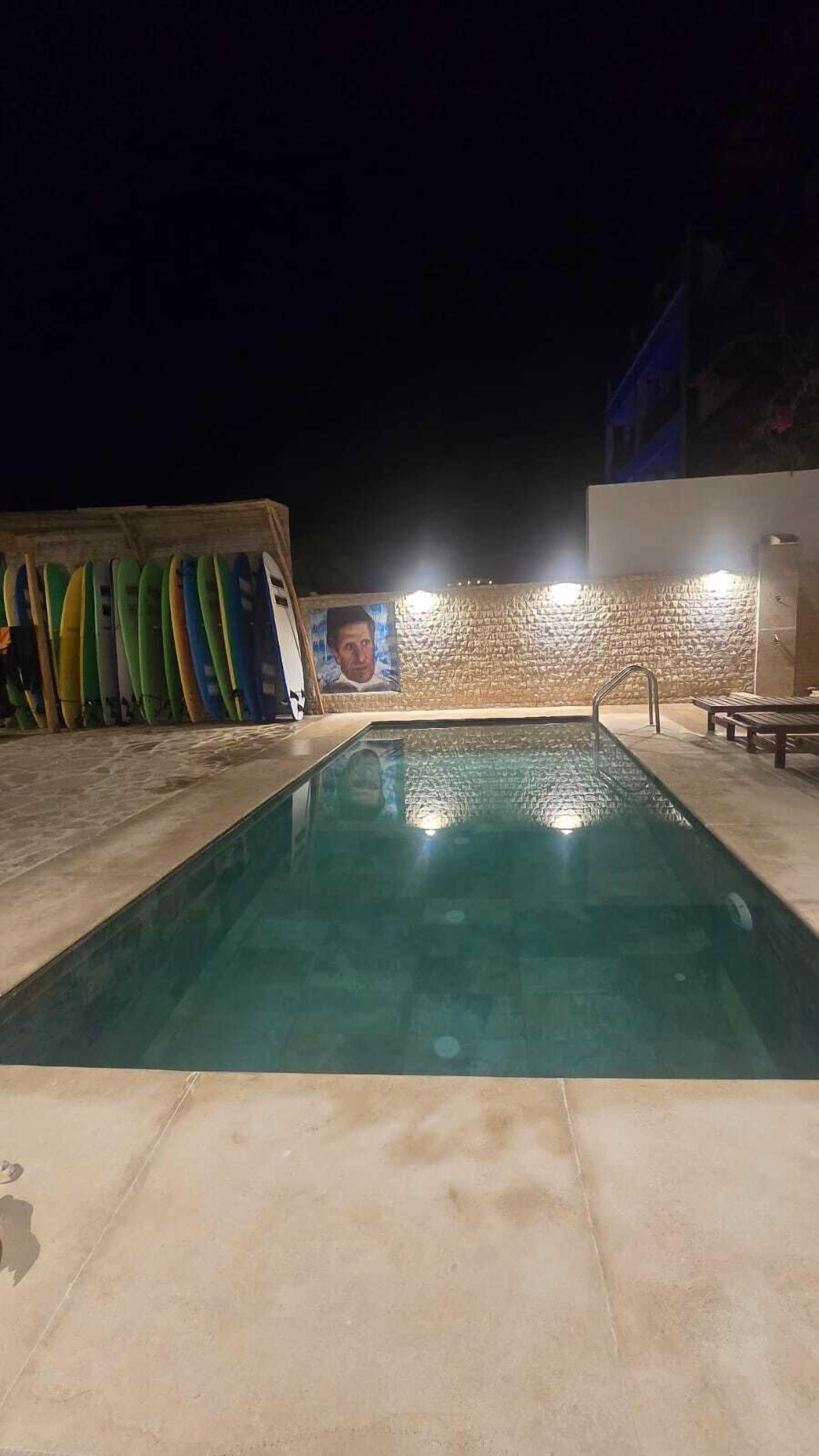 Une piscine avec un mur en pierre et une fresque en arrière-plan.
