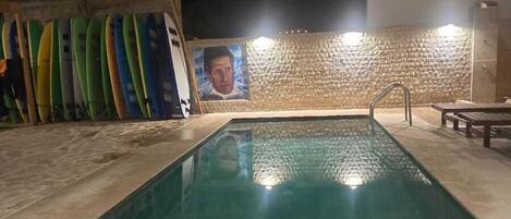 Une piscine avec un mur en pierre et une fresque en arrière-plan.