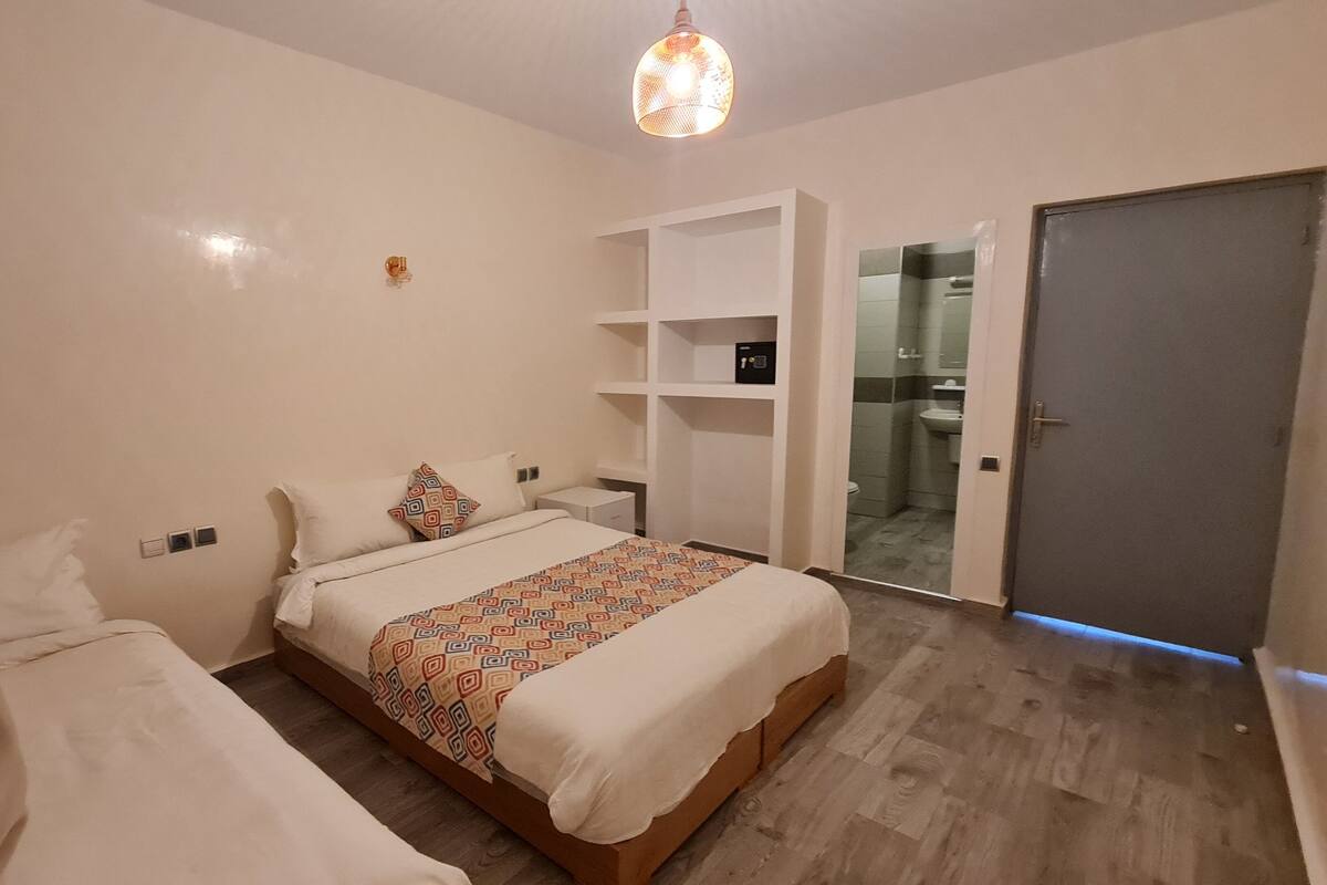 Una habitación de hotel con cama, armario, baño y puerta.