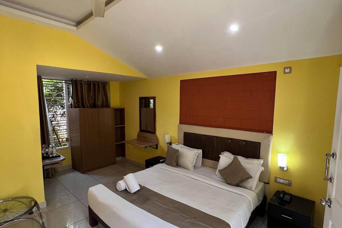 A hotel room with a bed, bedside table, nightstand, and a ceiling fan.