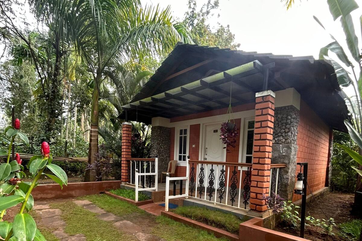 A house with a brick exterior, a porch with a railing, and a garden with grass and plants.