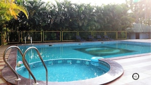 A swimming pool with two lanes, surrounded by a fence and palm trees.
