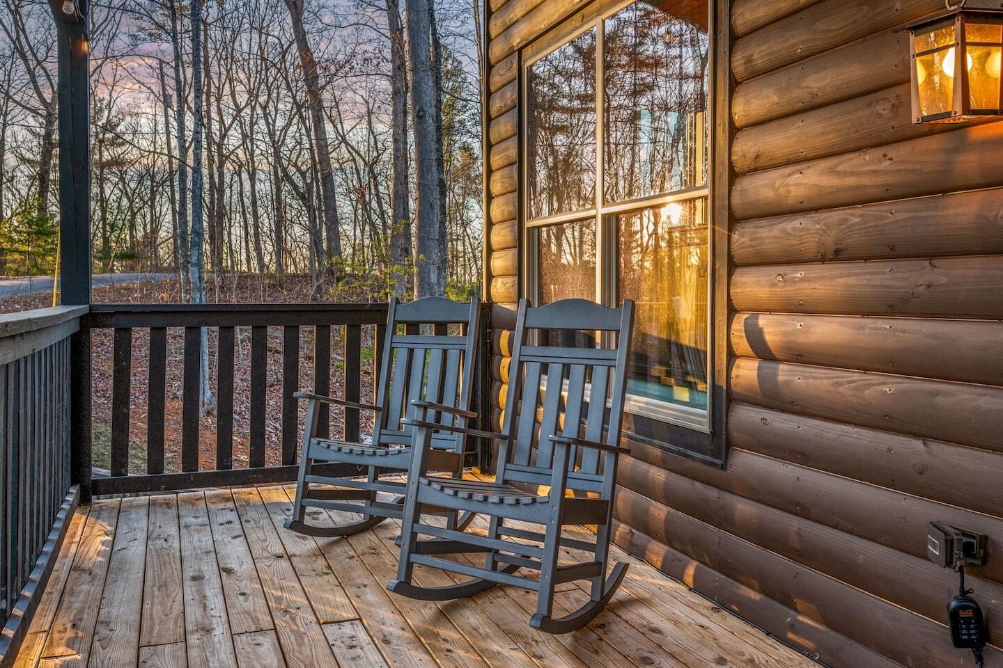 Eine Holzhütte mit Veranda, zwei Schaukelstühlen und einem Fenster mit Blick auf Bäume.