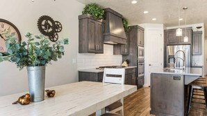 Una cocina moderna con armarios de madera oscura, una isla central y un reloj en la pared.