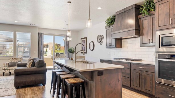 Una cocina moderna con armarios de madera oscura, electrodomésticos de acero inoxidable y una isla central con taburetes.